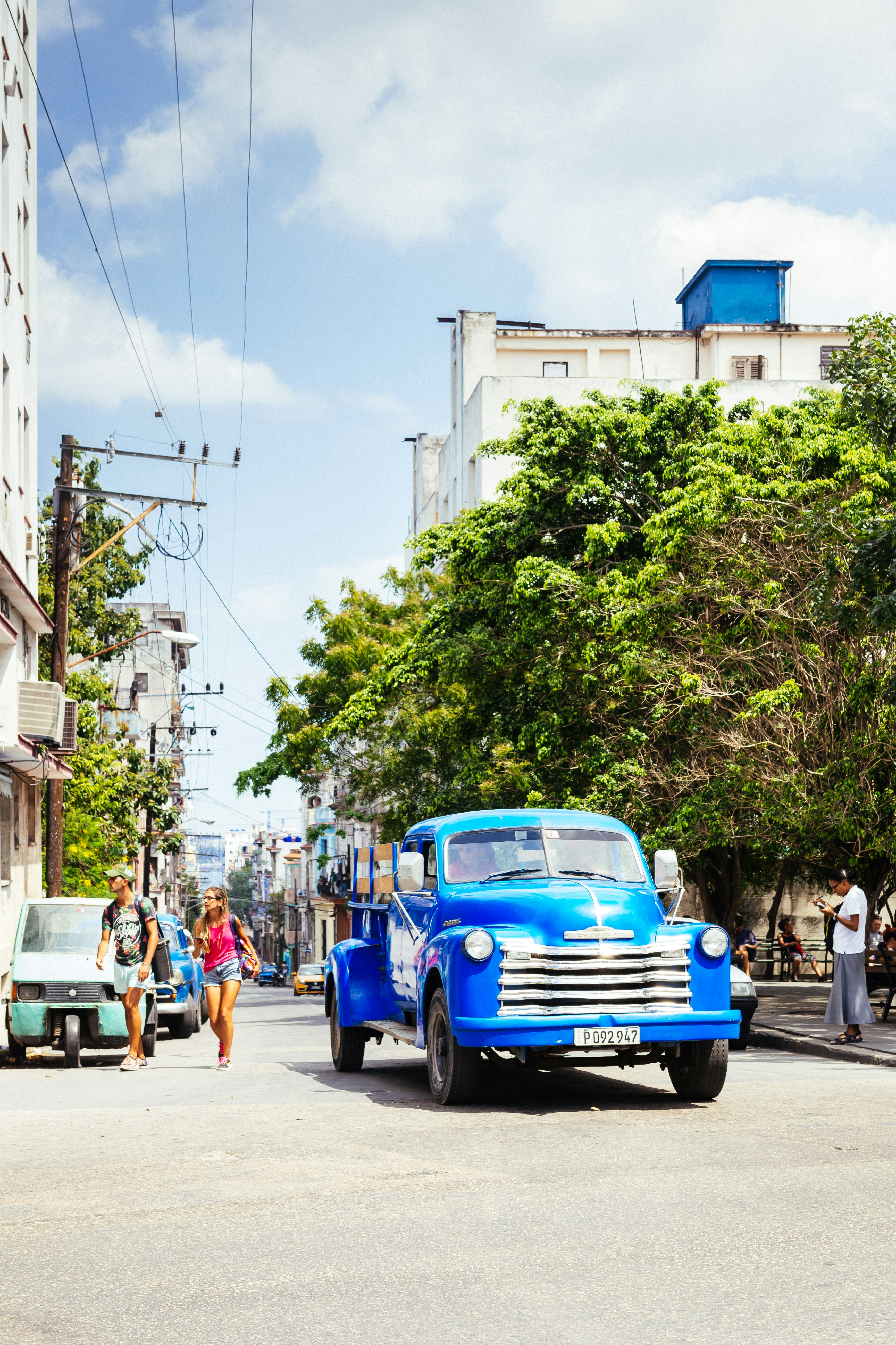 blue vehicle on road beside tree during daytime